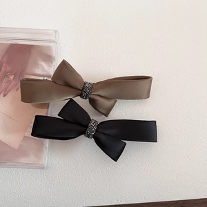 Detailed view of satin bow hair clips with sparkling rhinestones in black and khaki