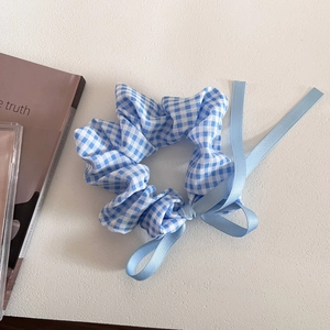 Close-up of blue plaid scrunchie with silk ribbons on a decorative background