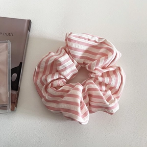 Detailed close-up of pink and white striped scrunchie with soft fabric texture