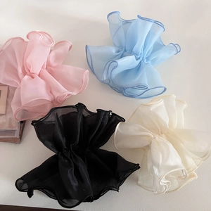 Close-up of four oversized organza scrunchies in pink, blue, black, and cream colors