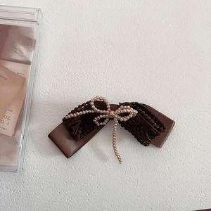 Close-up of vintage brown lace bow hair clip with delicate pearl fringe detail
