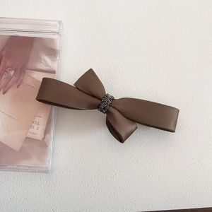 Macro detail of luxury brown satin bow hair clip with sparkling rhinestone center decoration