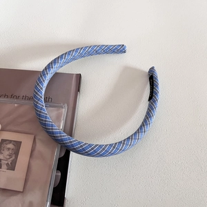 Detail eines blau-weiß karierten Stoff-Haarreifens mit Weblabel auf Vintage-Schreibtisch