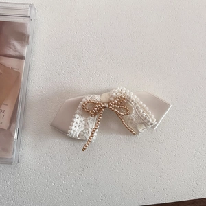 Close-up of elegant lace bow hair clip with champagne pearls and white satin details