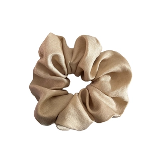 Elegant champagne gold satin scrunchie with a glossy silk texture and voluminous design