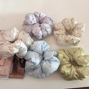 Detailed close-up of five colorful satin polka dot scrunchies in pastel colors