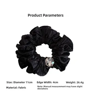 Detail of black satin scrunchie with sparkling rhinestone gem and ruffled edges