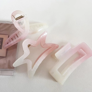 Close-up of pink gradient glitter hair claws in star and rectangle shapes on white surface