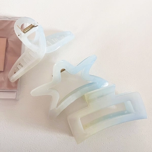 Close-up of pearlized gradient hair claws in star, cross, and hollow rectangle shapes