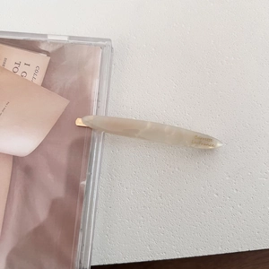 Detail of elegant beige marble acetate hair clip with golden metal base and engraving
