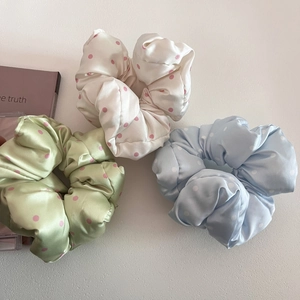 Detailed macro view of three satin polka dot scrunchies in pastel green, white and blue