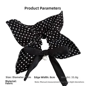 Close-up of oversized black polka dot scrunchie with large bow and pearl pendant detail