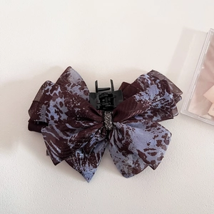 Macro shot of ink pattern fabric bow claw clip with elegant rhinestone center detail