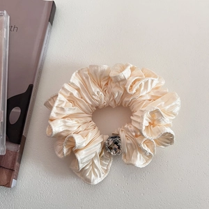 Detail of champagne gold satin scrunchie with a large faceted crystal centerpiece