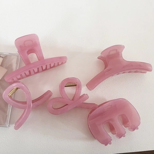 Set of five pink translucent acrylic hair claw clips in various shapes on white background