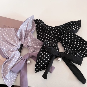 Close-up of retro polka dot scrunchies with bow tie and pearl charm on books