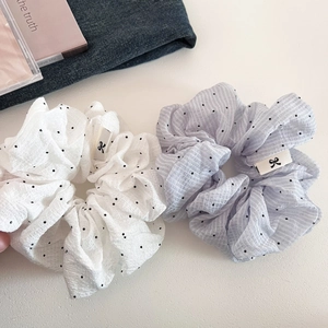 Close-up of white and light blue polka dot scrunchies with elegant ruffled texture
