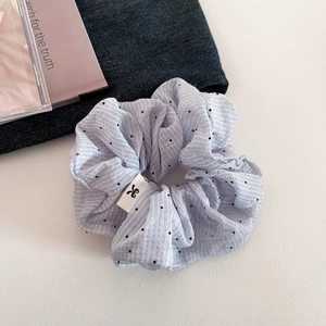 French style light blue polka dot scrunchie hair tie with logo label on denim backdrop