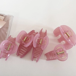 5-piece set of translucent pink resin claw clips with gold springs on white surface