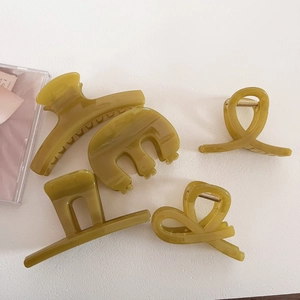 Set of five olive green resin hair claws in various shapes on a white surface