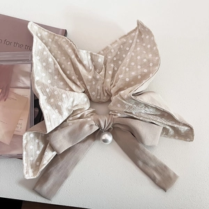 Detail of beige polka dot scrunchie with soft ribbon and elegant pearl pendant