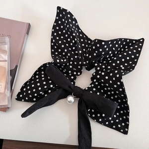 Polka dot bow scrunchie featuring a large black fabric knot and a faux pearl charm detail