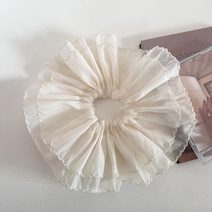 Detail of oversized cream double-layer mesh scrunchie with delicate ruffled edges and texture