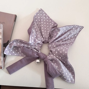 Close-up of lilac polka dot bow scrunchie with elegant pearl pendant detail
