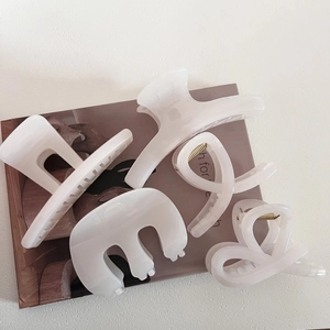Set of four cream-colored hair claws in square and curved styles on a magazine