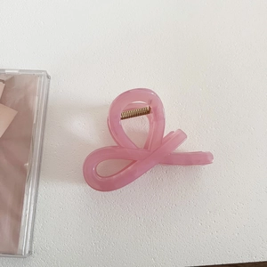 Detail of pink jelly-colored hair claw clip with twisted ribbon design and gold spring