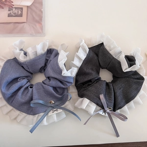 Close-up of pleated fabric scrunchies in grey-blue and black with lace trim and bow detail