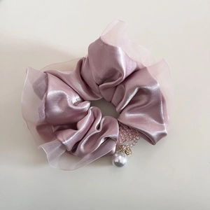 Dettaglio dello scrunchie in raso rosa con bordo in organza e pendente a perla raffinato