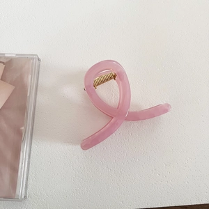 Close-up of pink jelly hair claw clip with cross design and golden metal spring