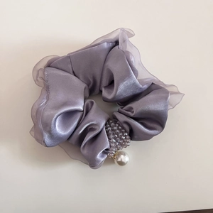 Dettaglio dell'elastico in raso lavanda con perline e ciondolo di perla bianca