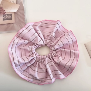 Détail d'un chouchou oversize à rayures roses avec volants et coutures de bord fines