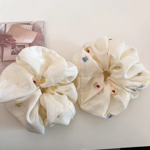 Close-up of beige scrunchies with colorful floral and fruit embroidery details