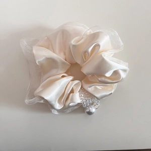 Dettaglio dell'elastico in raso crema con eleganti pendenti di perle e bordi in organza