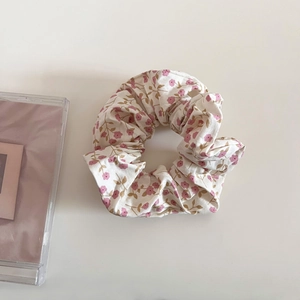 Détail de l'élastique à fleurs beiges avec motifs roses sur un bureau blanc minimaliste