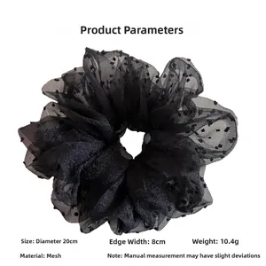 Detail view of oversized black polka dot mesh hair scrunchie showing 20cm diameter size