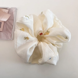 Close-up of beige oversized hair scrunchie with colorful floral embroidery and cotton texture