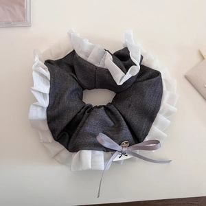 Detail view of grey denim scrunchie with white organza ruffles and bow pendant