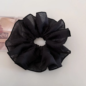 Detail of a large black sheer tulle scrunchie with soft pleats and elegant mesh texture