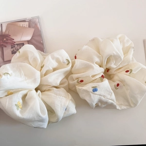 Close-up of beige scrunchies with colorful tulip embroidery and soft cotton texture
