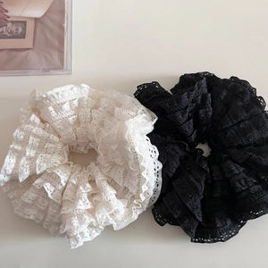 Détail de chouchous en dentelle superposée crème et noir avec des textures florales