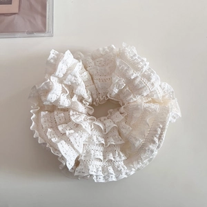 Détail d'un chouchou en dentelle blanche à plusieurs couches montrant la broderie fine