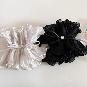 Macro detail of ruffled fabric scrunchie with a delicate bow and sparkling rhinestone