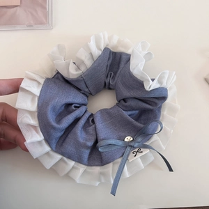 Detail of pleated hair scrunchie with blue fabric, white ruffles and small bow