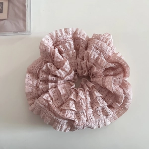 Gros plan sur un chouchou en dentelle rose avec texture creuse et design à couches