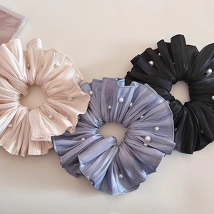 Detailansicht von drei Satin-Haargummis in Creme, Blau und Schwarz mit kleinen Perlen