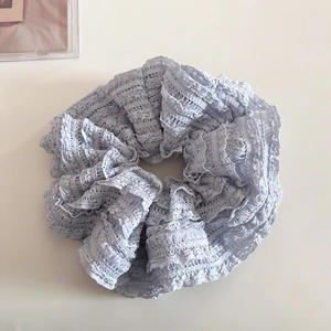 Gros plan sur un chouchou en dentelle bleu clair avec texture au crochet délicate